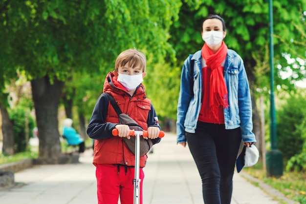 Premium Photo | Family in safety masks outdoors. riding boy on scooter in  park. boy wears medical face mask. coronavirus epidemic.