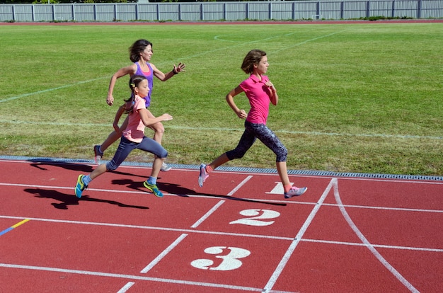 家族のスポーツとフィットネス 幸せな母とスタジアムで実行している子供は屋外 子供の健康的なアクティブなライフスタイルコンセプトを追跡します プレミアム写真