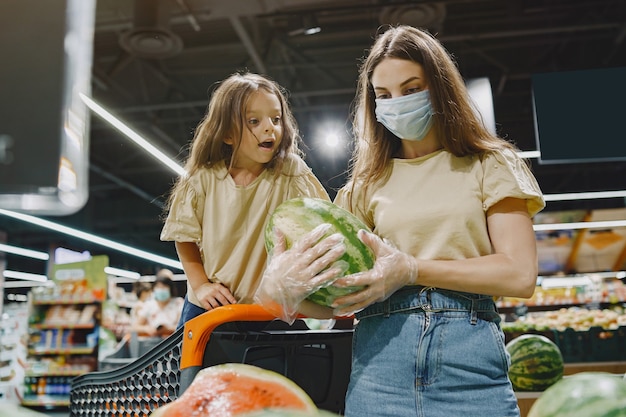 Family at the supermarket. woman in a protective mask. people choose vegetables. mother with daughter. coronavirus. Free Photo