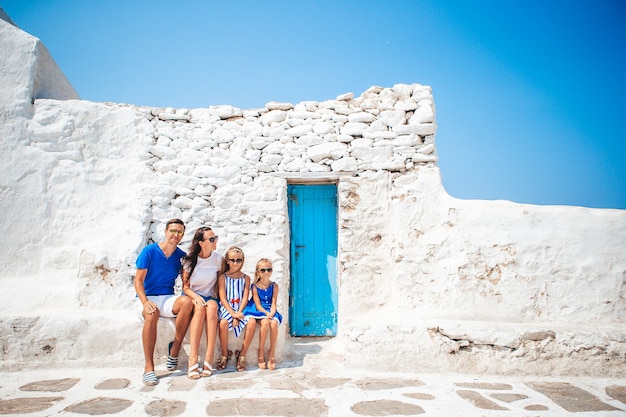 ヨーロッパでの家族旅行 ギリシャのミコノス島にある白い壁とカラフルなドアのある典型的なギリシャの伝統的な村の通りにいる親子 プレミアム写真