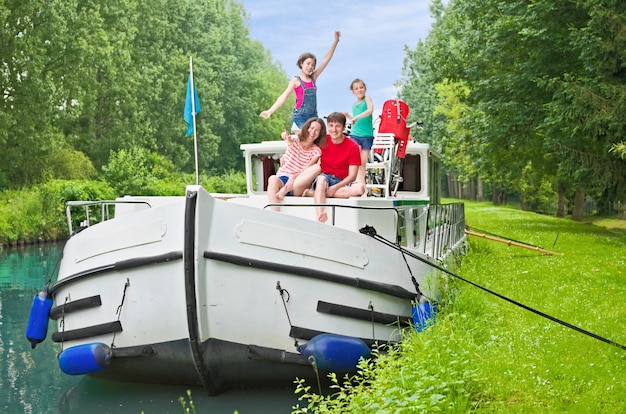 Family vacation, summer holiday travel on barge boat in canal, happy kids and parents having fun on river cruise trip in houseboat in france Premium Photo