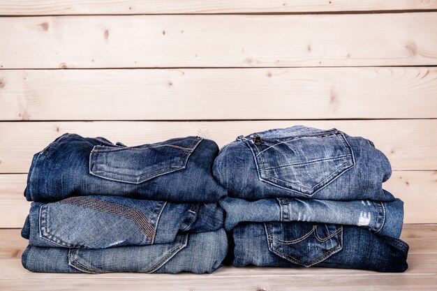 おしゃれな服 木製の背景にジーンズの山 プレミアム写真