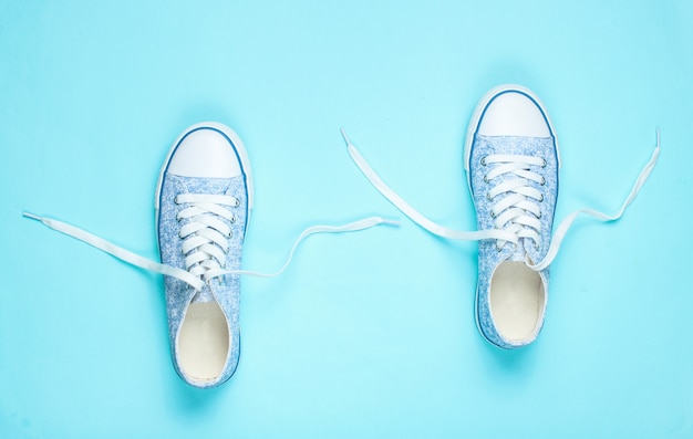 Premium Photo | Fashionable sneakers with untied laces on blue. top view