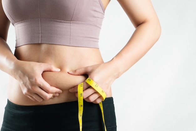 太った女性 太った腹 ぽっちゃり メジャーテープ 女性ダイエットライフスタイルコンセプトで過度の腹脂肪を持つ肥満女性の手 プレミアム写真