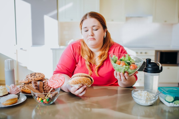 Premium Photo Fat Young Woman In Kitchen Sitting And Eating Food