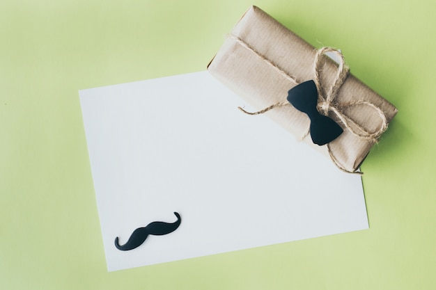 Father's day. gift package wrapped with paper and rope with a decorative bow-tie on green background. copyspace Premium Photo