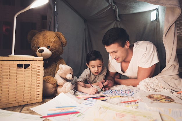 Premium Photo | Father and son are drawing with color pencils on paper.