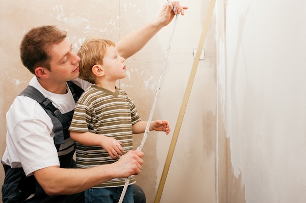 Father and son measuring dry wall Premium Photo