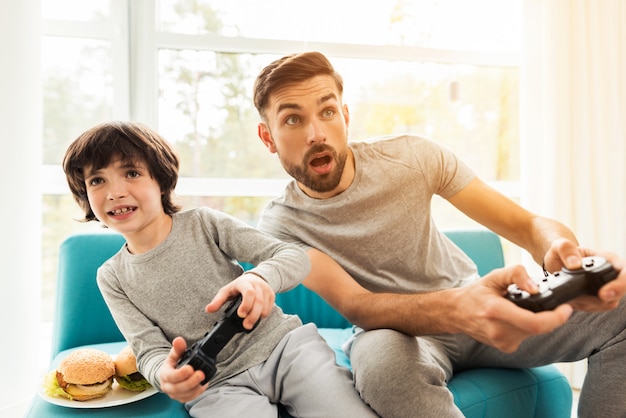 Father and son sitting and playing on console. Premium Photo