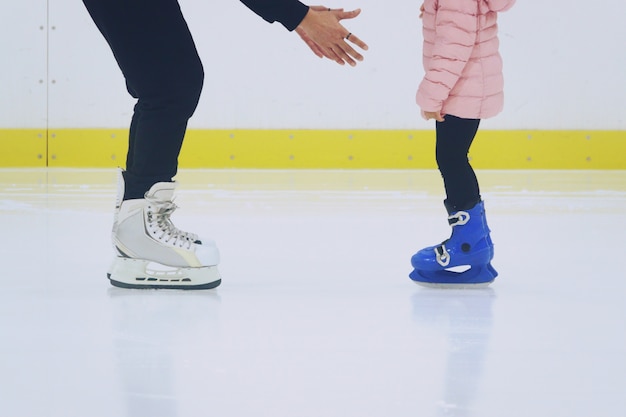 Premium Photo | Father teaching daughter to skate at ice-skating rink