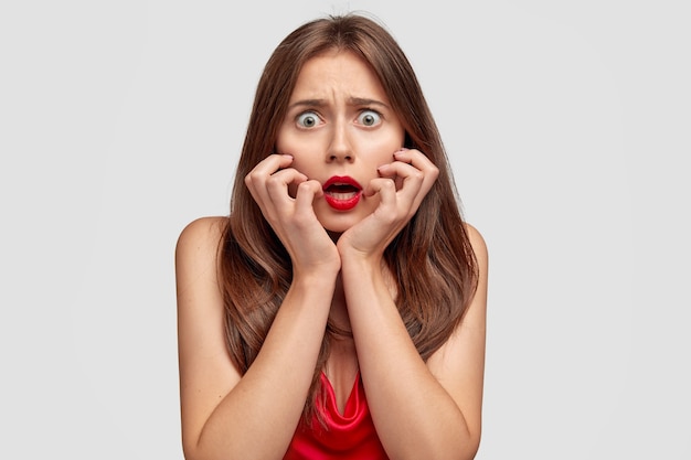 Free Photo | Fearful brunette young woman posing against the white wall