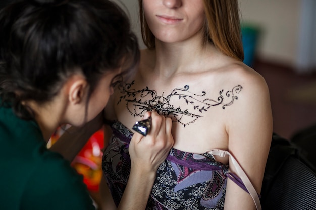 女性アーティストの女性の胸に一時的な刺青の入れ墨を描く 無料の写真