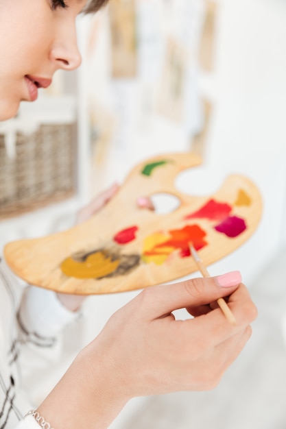 Female artist holding palette and mixing paint colors Free Photo