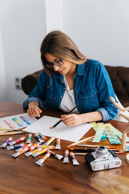 Female artist painting at desk | Free Photo