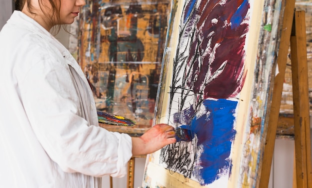 Female artist painting with brush on canvas at workshop Free Photo