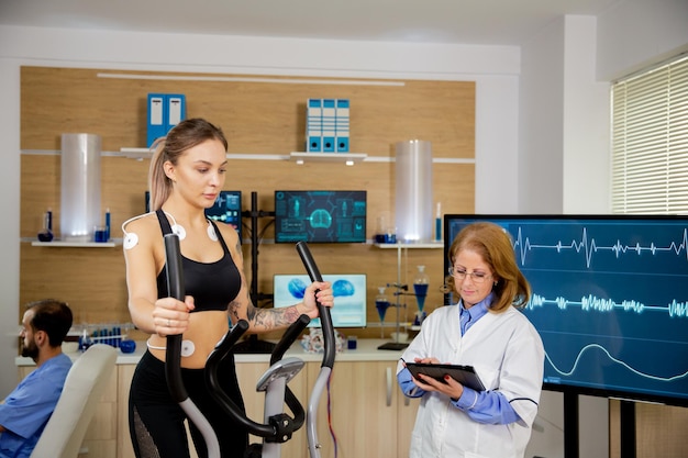 Premium Photo | Female athlete running tests on the stepper and doctor ...