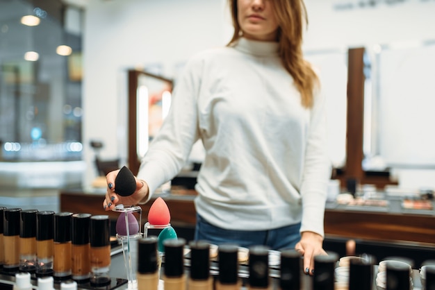 Premium Photo | Female customer against showcase in the makeup shop ...