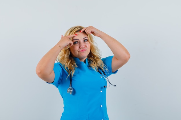 Free Photo | Female doctor pinching her pimples in blue uniform