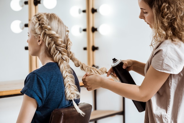 Female hairdresser making hairstyle to blonde woman in beauty salon Free Photo