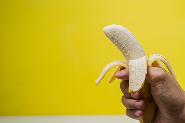 Premium Photo | Female hand holding a banana on yellow background ...