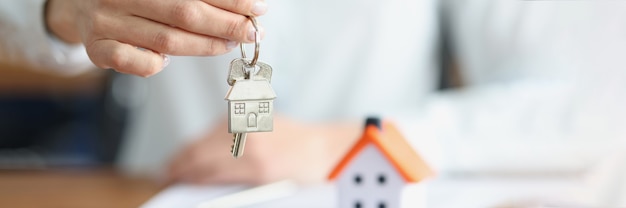 premium-photo-female-hand-holding-keys-with-keychain-near-toy-house