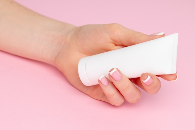 Premium Photo | Female hand holding skincare product bottle on pink