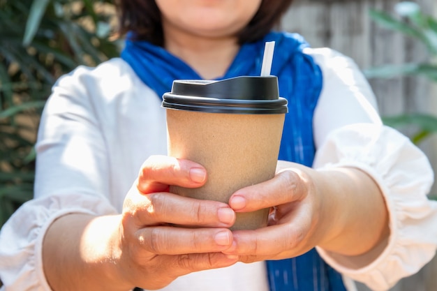 紙コップのコーヒーを持った女性の手が奪う 完璧なマニキュアの女性の手に紙コップ プレミアム写真