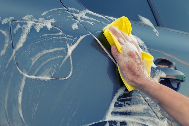 Premium Photo | Female hand with yellow sponge in soapy foam washes the car