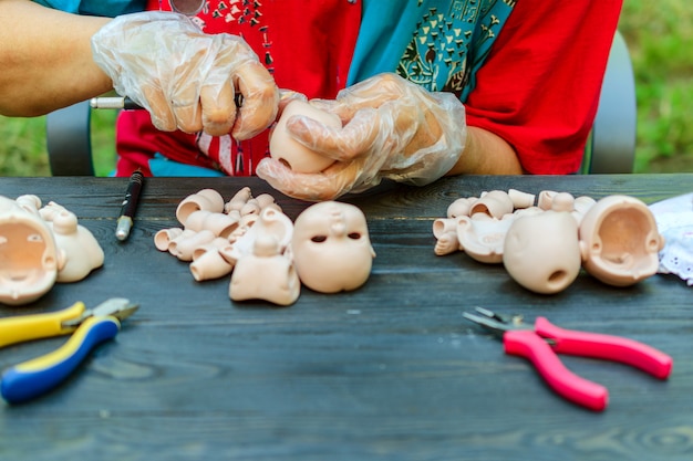 Female hands make dolls of bjd in workplace. processing workpiece. Premium Photo