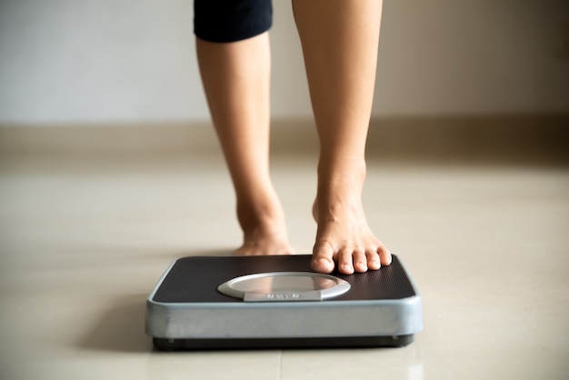 Female leg stepping on weigh scales. healthy lifestyle, food and sport concept. Premium Photo