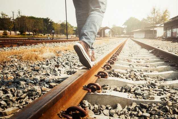 Female legs in sneakers on the rail of the railway. Free Photo
