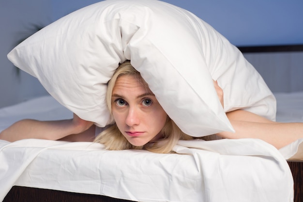 Kobieta Leżąca Na łóżku I Zamykająca Uszy Poduszką - Zdjęcie Premium
