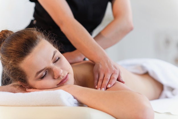 Female massaeur hands doing massage to young woman in spa center ...