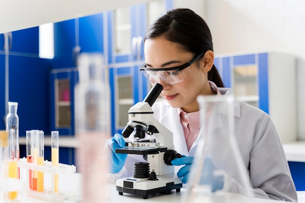 Female scientist in the lab looking through microscope Free Photo