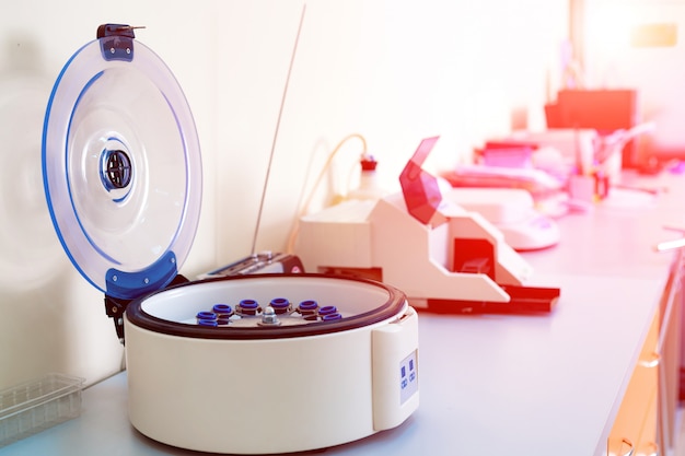 Female scientist loads some vials of liquid into a centrifuge in a laboratory. Premium Photo