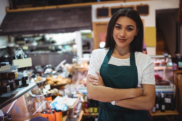 Female staff standing with arms crossed in super market Free Photo