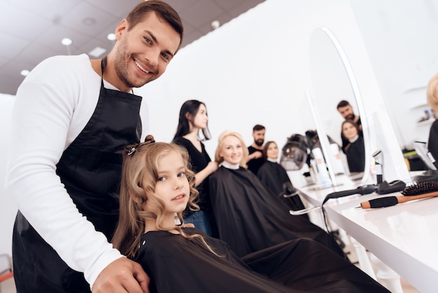 Female Stylist Does Haircut Of Little Girl With Curly Hair