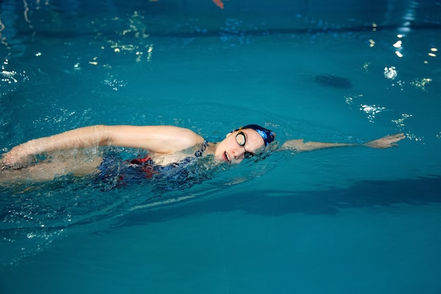 Premium Photo | Female swimmer in swimsuit, cap and glasses swimming on ...