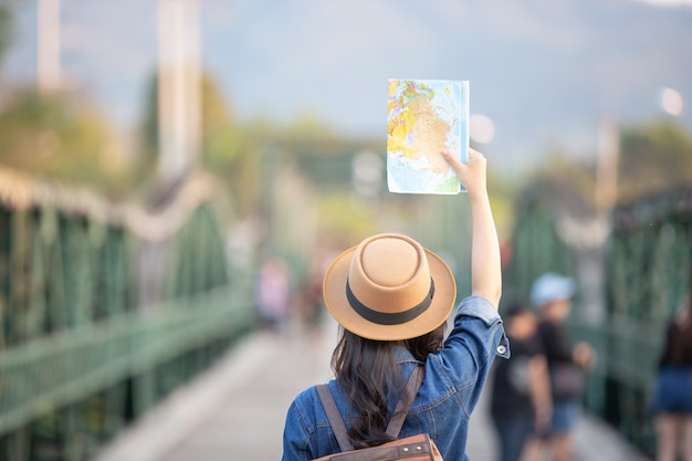 Female tourists on hand have a happy travel map. Free Photo