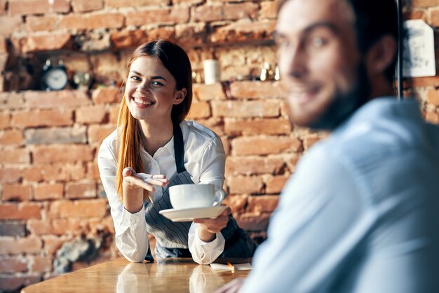 顧客カフェを提供するコーヒーのカップを持つ女性ウェイター プレミアム写真