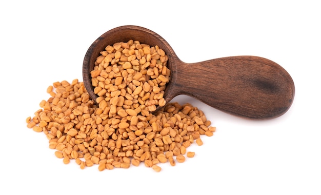 Fenugreek seeds in wooden spoon, isolated shambala, helba seeds. Premium Photo