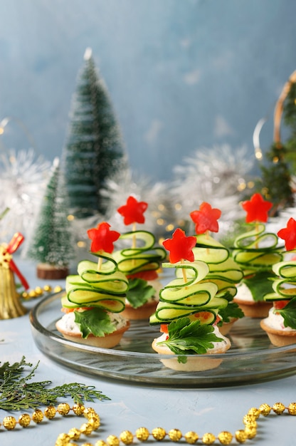 きゅうりとピーマンの星のクリスマスツリーの形をしたお祝いのカナッペ クローズアップのワイン2杯と明るい青の背景に プレミアム写真