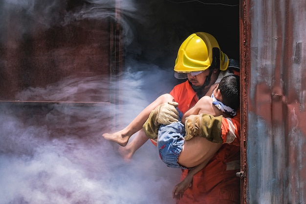 Firefighter holding child boy to save him in fire and smoke Premium Photo