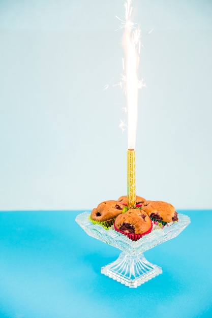 ピンクの背景に対して透明なcakestandのカップケーキの真ん中に花火の輝き 無料の写真