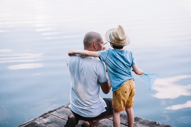 Fisherman with his son holding fishing net near lake Free Photo
