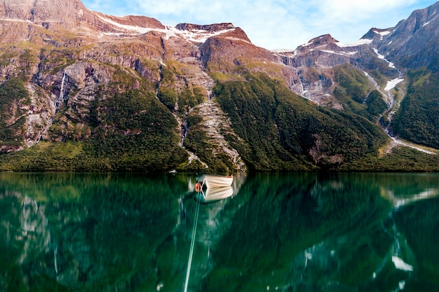 Fishing boat on a still lake with high mountains in background Free Photo