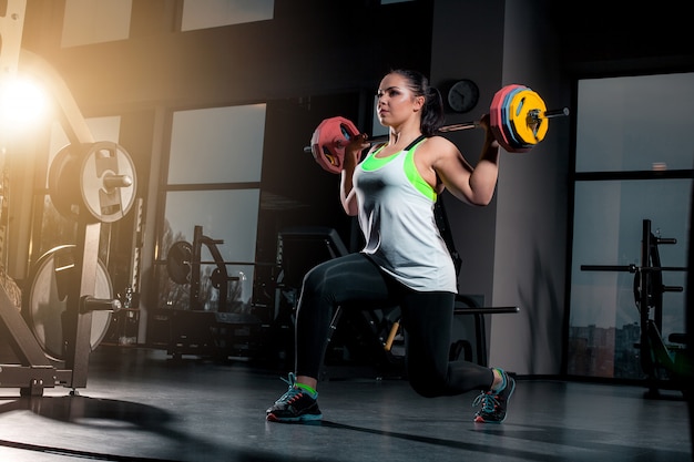 Fit young woman lifting barbells looking focused, working out in a gym Free Photo