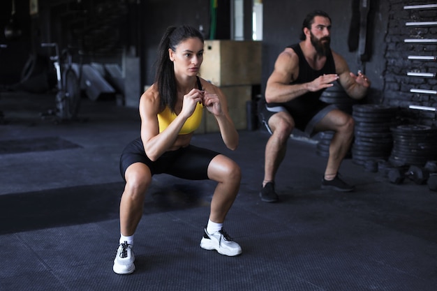 Premium Photo | Fitness couple in sportswear doing squat exercises at gym.