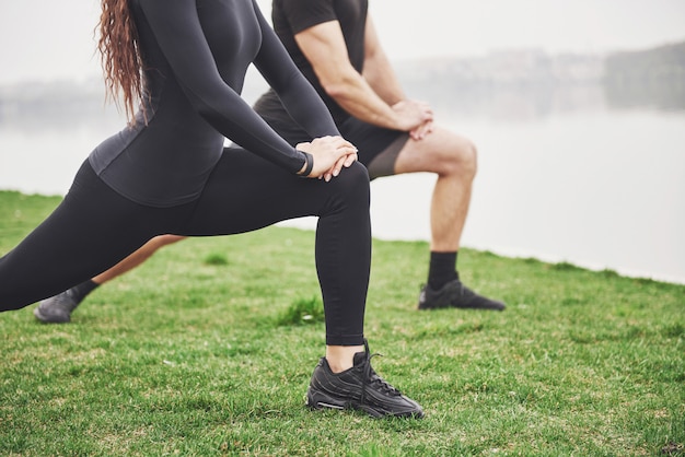 Fitness couple stretching outdoors in park near the water. young bearded man and woman exercising together in morning Free Photo