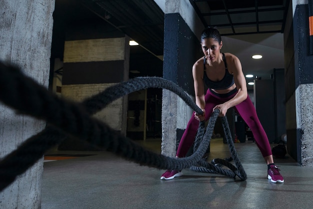 Fitness woman working out with battle ropes in the gym Free Photo